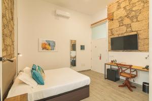 a bedroom with a bed and a desk and a television at Hotel The Cathedral Vegueta in Las Palmas de Gran Canaria