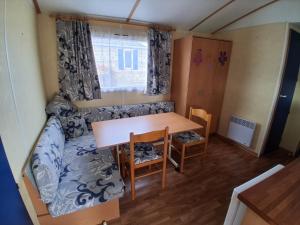 a small room with a table and a couch at Camping du Mesnil - Gaia Vacances in Saint-Aubin-sur-Mer