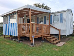 a tiny house with a porch and a staircase at Camping du Mesnil - Gaia Vacances in Saint-Aubin-sur-Mer +4 photos
