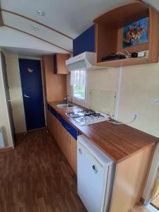 a small kitchen with a stove and a sink at Camping du Mesnil - Gaia Vacances in Saint-Aubin-sur-Mer