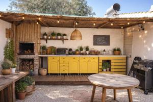 an outdoor kitchen with yellow cabinets and a table at Villa Madeira in Silves
