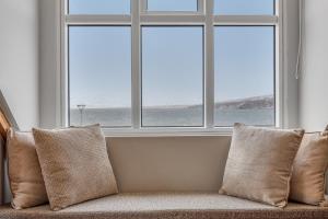 a couch with pillows sitting in front of a window at Bryggjan Boutique Hotel in Akureyri
