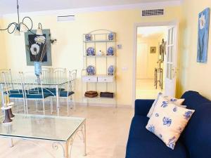 a living room with a blue couch and a glass table at Spectacular beachfront apartment in Estepona
