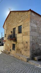 a stone building with two windows and a balcony at Cominhos & Quartilhos in Sortelha