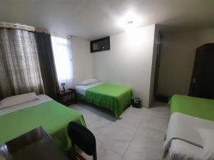 a room with two beds with green sheets at Hotel Cordillera Real in Sogamoso +4 photos