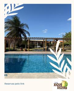 a swimming pool with a palm tree in the background at Hotel pousada Xique Xique in Piranhas