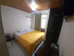 a bedroom with a bed with a yellow blanket at Hotel Cordillera Real in Sogamoso