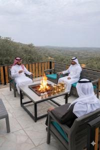 a group of people sitting around a fire on a deck at شاليه غصن in Ajloun