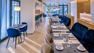 a restaurant with long tables and blue chairs at Hotel Infante Santo - Lisboa in Lisbon