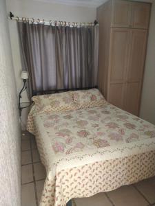 a small bedroom with a bed with a floral bedspread at Cabañas ANANDA KANAN in Villa Giardino