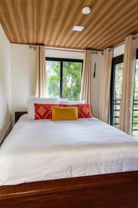 a bedroom with a large white bed with red and yellow pillows at Casa Bajareque in Cerro Punta