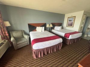 a hotel room with two beds and a chair at Budget Host Inn in Salina +3 photos