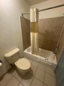 a bathroom with a toilet and a shower and a tub at Budget Host Inn in Salina