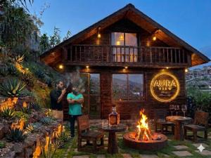 two people standing in front of a log cabin with a fire at AURA View in Nuwara Eliya