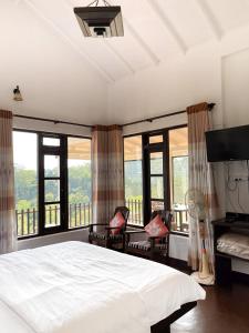 a bedroom with a large bed and large windows at Ella Repose in Ella