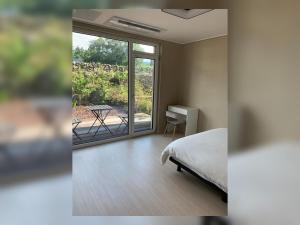 a bedroom with a bed and a view of a patio at Jeju Teracehill Pension in Jeju