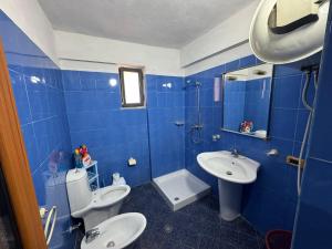 a blue tiled bathroom with two toilets and a sink at Kapllani Guest House in Durrës