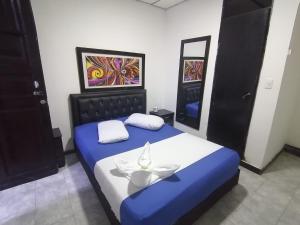 a bedroom with a blue and white bed and two mirrors at Hospedaje Luna Dorada in Manizales