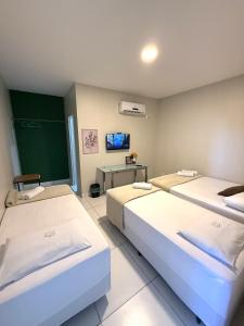 a room with two beds and a tv in it at Pousada Vasconcelos Tianguá in Tianguá