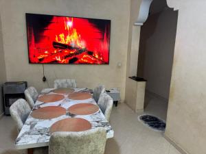 a dining room with a table and a fire on the wall at Apparemment Noucer in Derroua