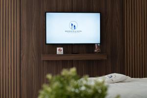 a flat screen tv on a wall with a bed at Suites Nador in Nador