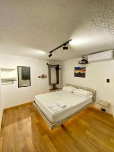 a bedroom with a large white bed and wooden floors at Hotel Grand ilama in Cali
