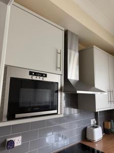 a kitchen with white cabinets and a microwave at Cobble retreat high street in Hastings
