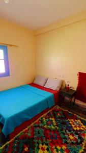 a bedroom with two beds and a colorful rug at Gite Boutferda in Bou Tferda
