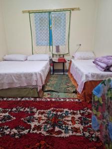 a room with two beds and a rug at Gite Boutferda in Bou Tferda