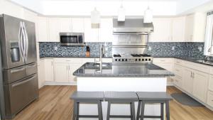 a kitchen with white cabinets and stainless steel appliances at 8 Bedrooms With A Pool - 404 Fourth Avenue in West Cape May