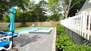 a backyard pool with an umbrella and chairs and a pool at 8 Bedrooms With A Pool - 404 Fourth Avenue in West Cape May