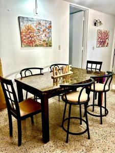 a dining room with a table and chairs and a painting at Nice and Cozy House in the Greater Ponce Area in Ponce +14 photos