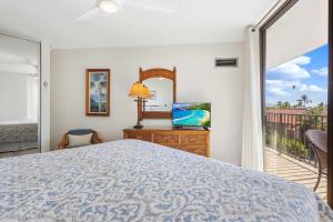 a bedroom with a bed and a television and a balcony at Penthouse Oceanview Vistas in Kihei