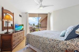 a bedroom with a bed and a tv and a window at Penthouse Oceanview Vistas in Kihei
