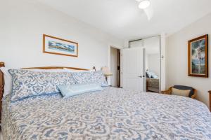 a bedroom with a large bed with a blue blanket at Penthouse Oceanview Vistas in Kihei