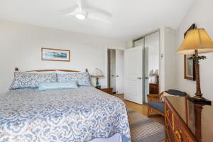 a bedroom with a bed with a blue and white bedspread at Penthouse Oceanview Vistas in Kihei +29 photos