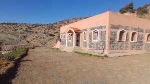 a small pink building in the middle of a dirt road at Gite Boutferda in Bou Tferda