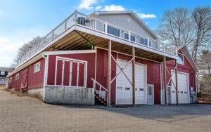 a red barn with a balcony on top of it at Phoenix Aerie Birds-Eye Harbor Views, Maritime Loft, Harbor Watch Sunrise Deck in Southwest Harbor