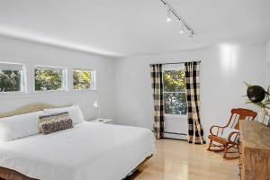 a white bedroom with a bed and two windows at Northern Nest MDI Lakefront Single-Level, Dual King Bedrooms & Private Dock in Pretty Marsh