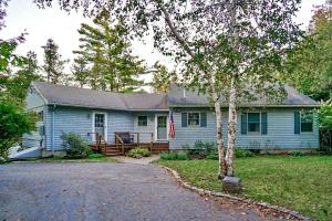 a blue house with a tree in front of it at Northern Nest MDI Lakefront Single-Level, Dual King Bedrooms & Private Dock in Pretty Marsh