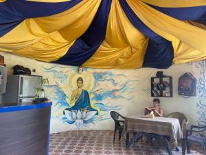a person sitting at a table with a painting on the wall at Jungle Nirvana Retreat in Meghauli