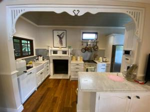 a large kitchen with white cabinets and a counter top at The Haven Cottage Point Sydney in Cowan