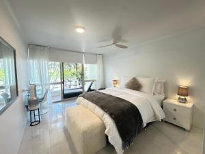 a white bedroom with a bed and a large window at Noosa Luxury Apartment in Noosa Heads