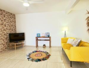 a living room with a yellow couch and a television at Appartement spacieux La Vanille 2 in Ducos