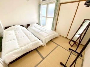 a white bed in a room with a window at LemonRooms in Aomori