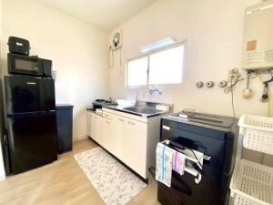 a kitchen with a black refrigerator and a sink at LemonRooms in Aomori