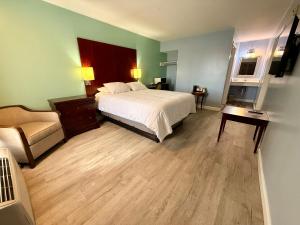 a hotel room with a bed and a chair at Americas Best Value Inn Suites & Studios Blytheville by Sonesta in Blytheville