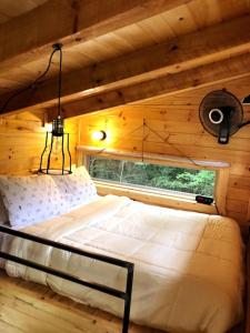 a bed in a wooden room with a window at Theodore Tiny Cabin- RRG Hot Tub Pet Friendly in Slade