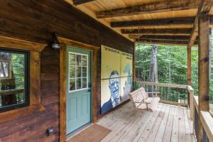 a wooden porch with a door and a bench on it at Theodore Tiny Cabin- RRG Hot Tub Pet Friendly in Slade