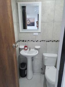 a bathroom with a sink and a toilet and a mirror at Hotel Chemy in Quito